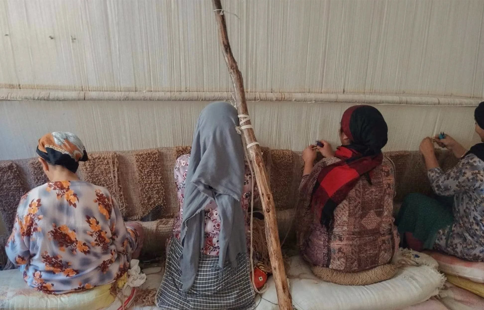 Weavers tying knots at the loom in the High Atlas workshop